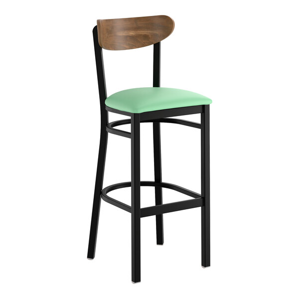 A bar stool with a black metal frame, a seafoam green vinyl seat, and a curved vintage wood backrest.
