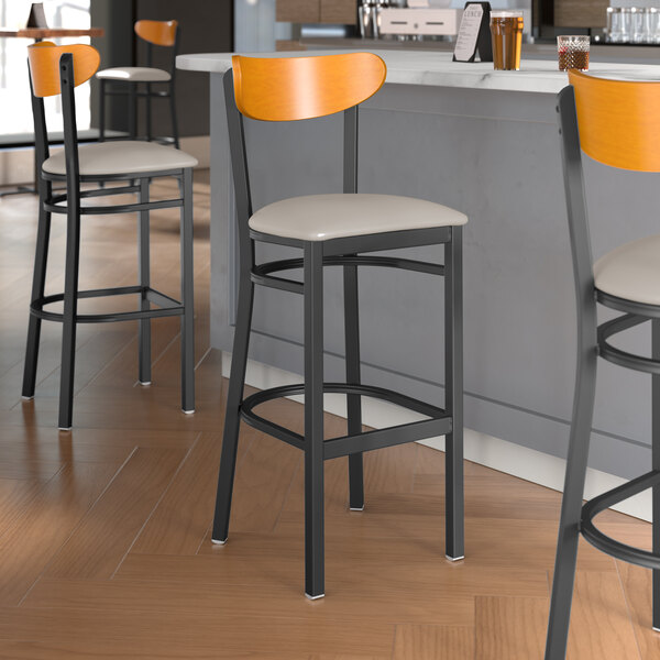 Lancaster Table & Seating black bar stool with light gray vinyl and cherry wood back.