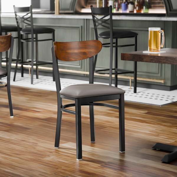 A black metal chair with a dark gray vinyl seat and a curved vintage wood backrest.