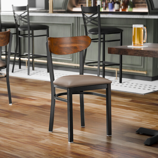 A black metal chair with a taupe vinyl seat and a curved vintage wood backrest.