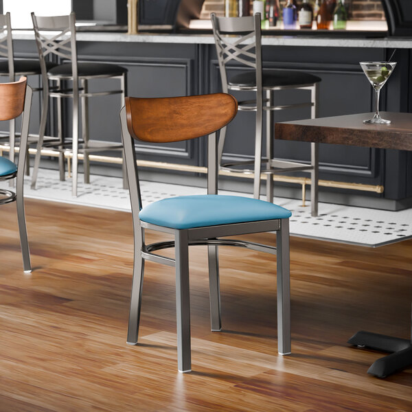 A metal chair with a blue vinyl seat and an antique walnut wood backrest.