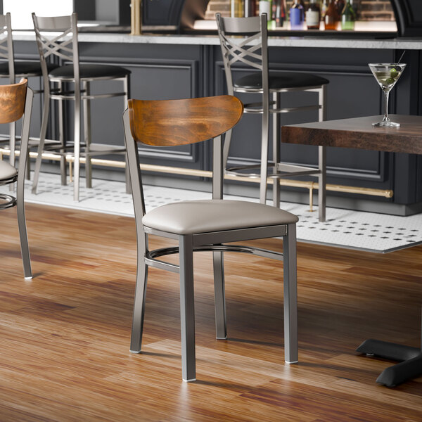 A metal chair with a light gray vinyl seat and a curved vintage wood backrest.