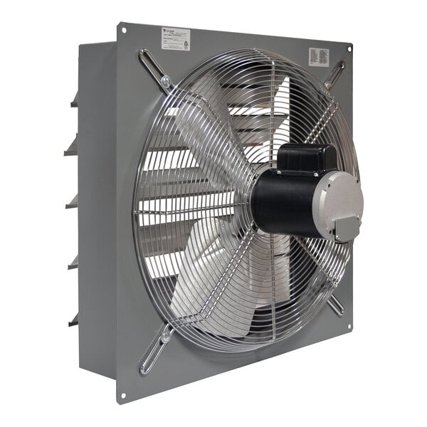 A large industrial wall-mounted exhaust fan with a metal frame, protective wire grill, and rear louvers.
