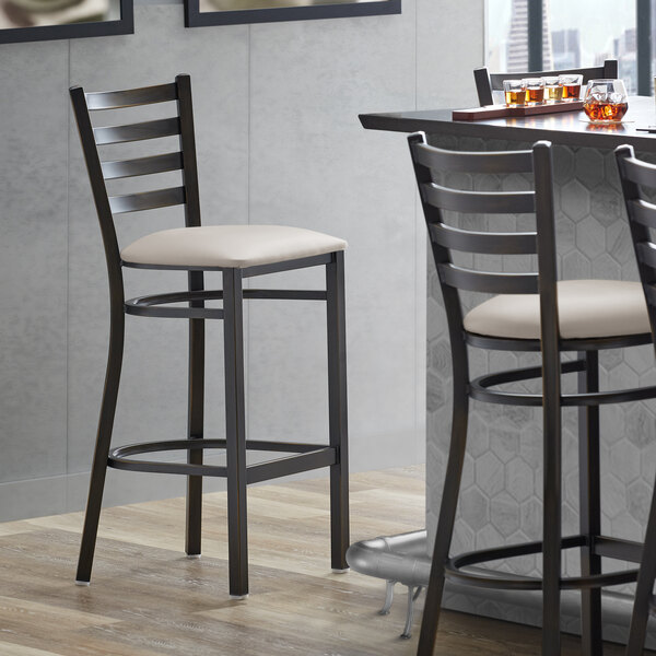 A Lancaster Table & Seating bar stool with light gray vinyl padded seat.