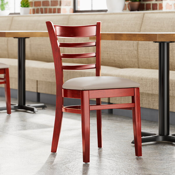 A Lancaster Table & Seating wood restaurant chair with a light gray vinyl seat.