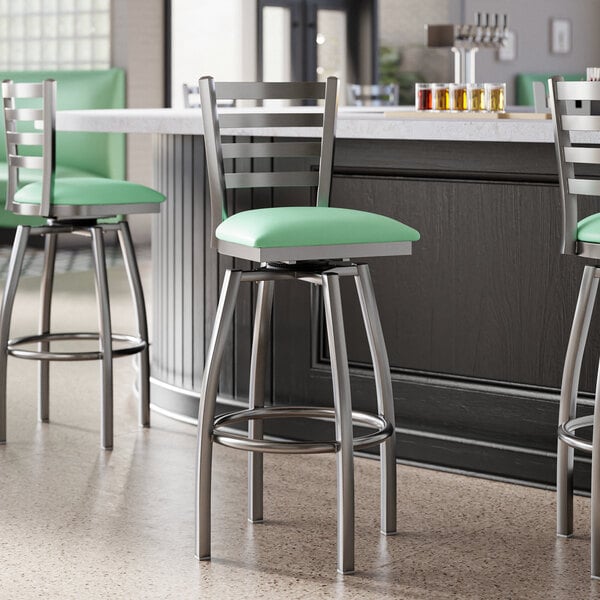 Lancaster Table & Seating clear coat finish ladder back swivel bar stools with seafoam vinyl padded seats.