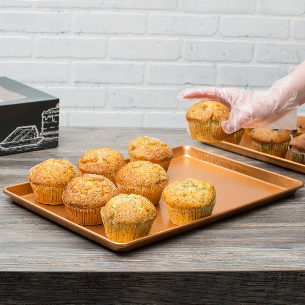 A person holding a Chicago Metallic bakery display tray with a muffin in their hand.