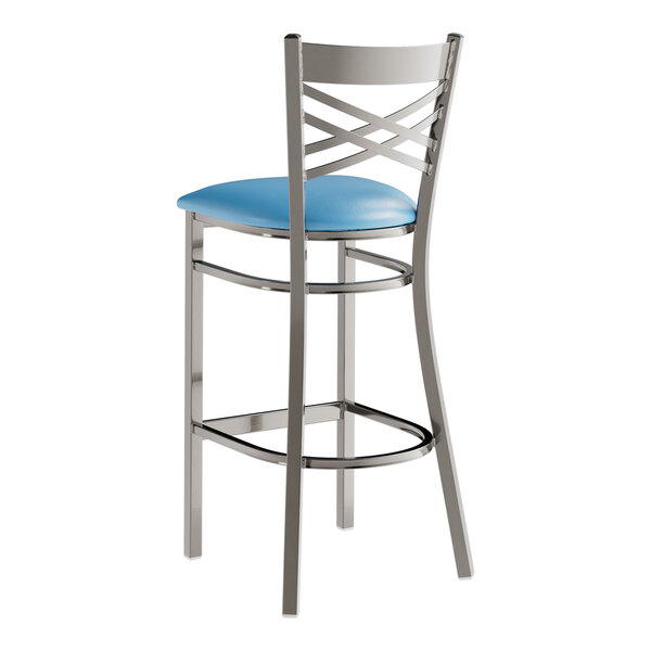 A Lancaster Table & Seating clear coated metal cross back bar stool with a blue vinyl padded seat.