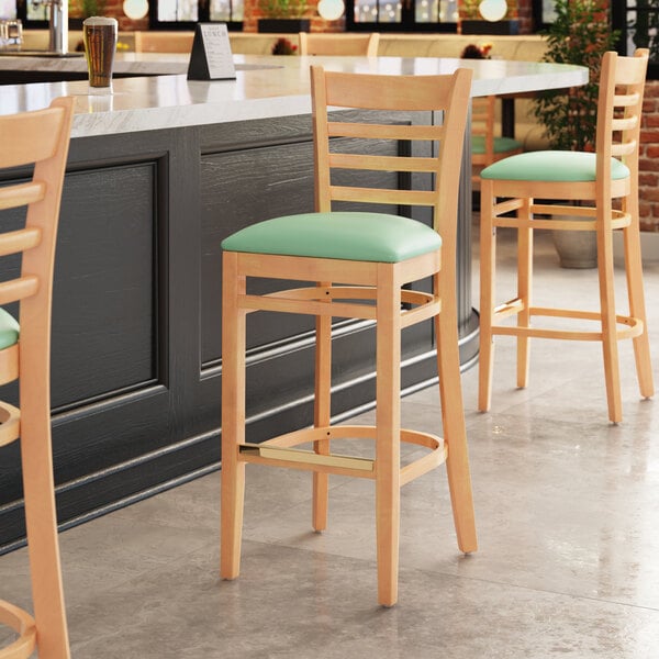 A Lancaster Table & Seating wood ladder back bar stool with a detached seafoam vinyl seat.