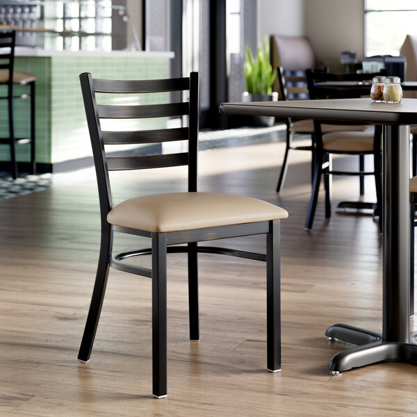 A ladder back chair with a distressed copper finish and a taupe vinyl padded seat.
