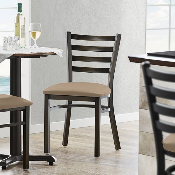 A Lancaster Table & Seating Distressed Copper ladder back chair with a taupe vinyl padded seat.