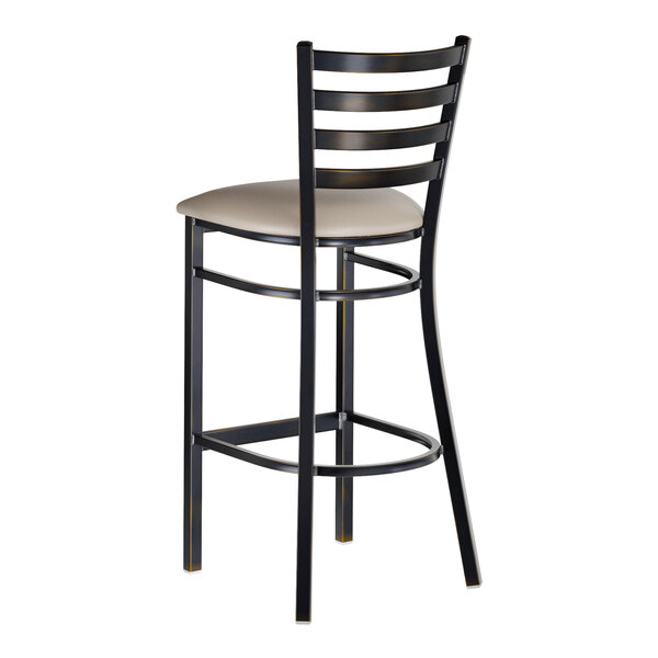 A metal bar stool with a ladder back design and a dark gray vinyl padded seat.