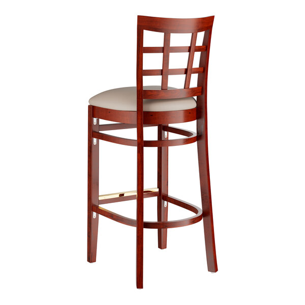 A Lancaster Table & Seating mahogany wood bar stool with a light gray cushion on the seat.