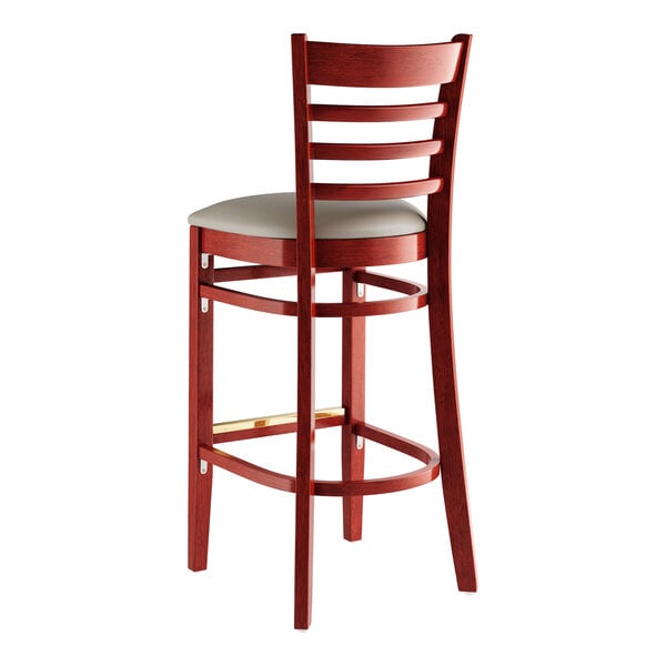 A Lancaster Table & Seating mahogany wood bar stool with a dark grey vinyl seat.