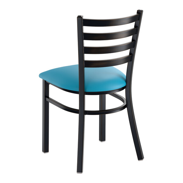 A black ladder back chair with a blue vinyl padded seat and a distressed copper finish.