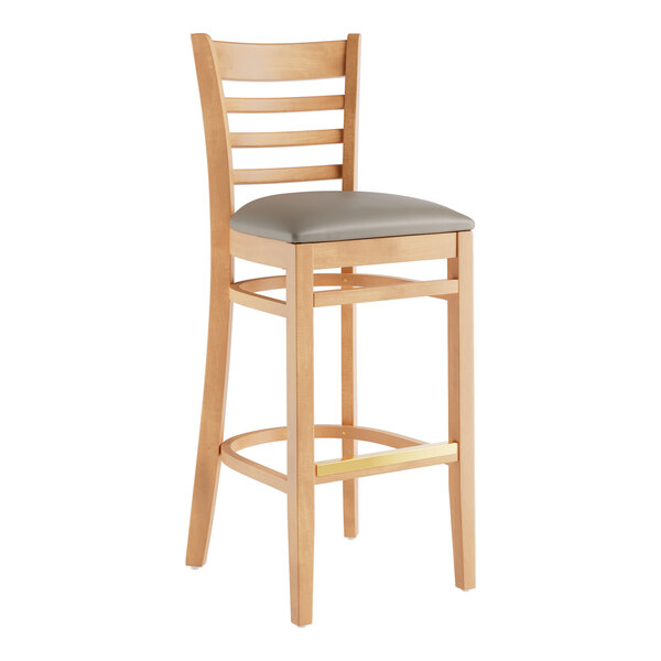 A Lancaster Table & Seating wooden bar stool with a dark gray cushion on the seat.