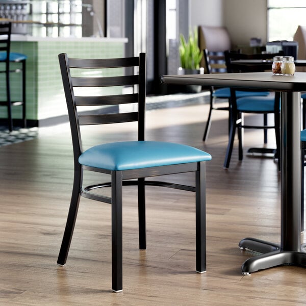 A black ladder back chair with a blue vinyl padded seat, designed for dining or restaurant use.