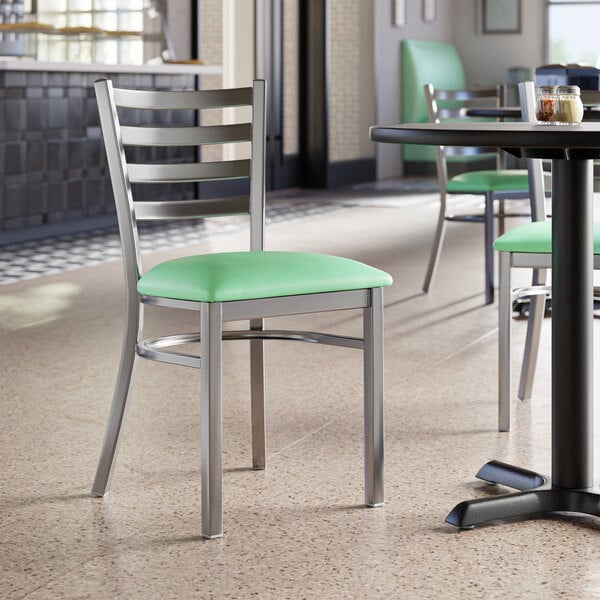 A Lancaster Table & Seating Ladder Back Chair with Seafoam Vinyl Seat on a table in a restaurant.