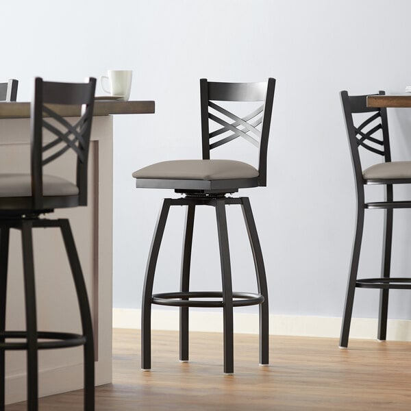 A Lancaster Table & Seating black swivel bar stool with dark gray vinyl padded seat.