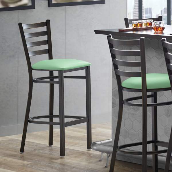A Lancaster Table & Seating ladder back bar stool with a seafoam green cushion.