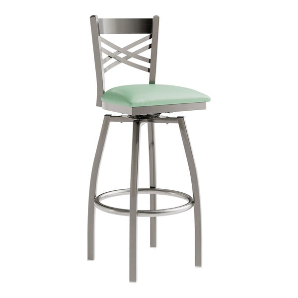 A Lancaster Table & Seating clear coat metal cross back swivel bar stool with a seafoam vinyl padded seat.