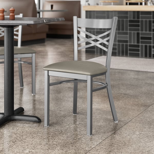 A Lancaster Table & Seating cross back chair with dark gray vinyl seat at a table in a restaurant.