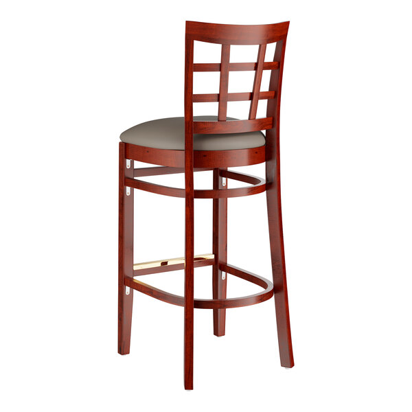 A Lancaster Table & Seating mahogany wood bar stool with a dark gray vinyl seat.
