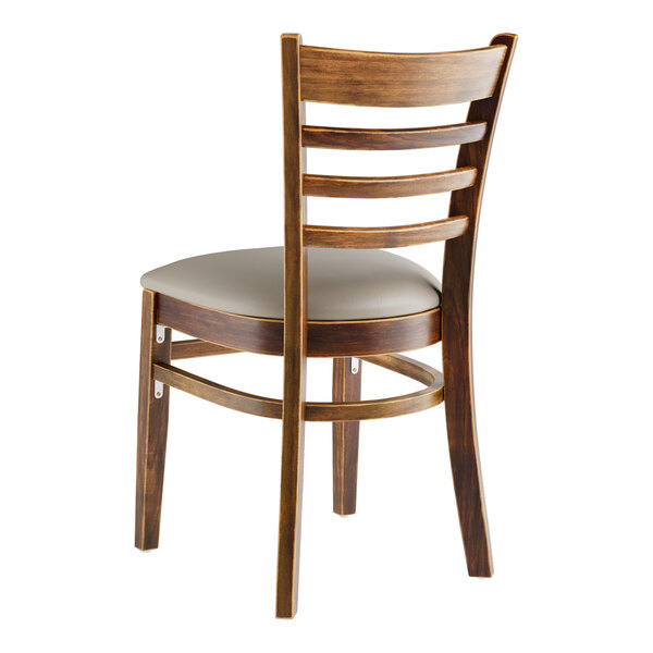 A Lancaster Table & Seating wooden ladder back chair with a dark gray vinyl seat.