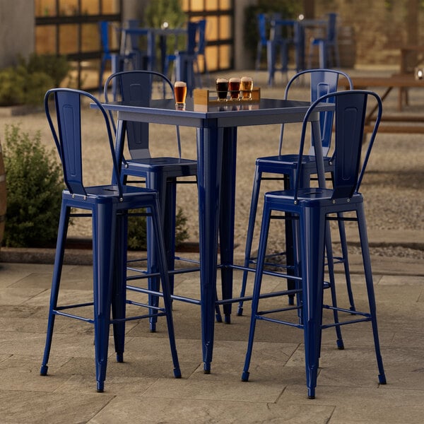 A Lancaster Table & Seating blue metal bar table with four blue metal barstools.