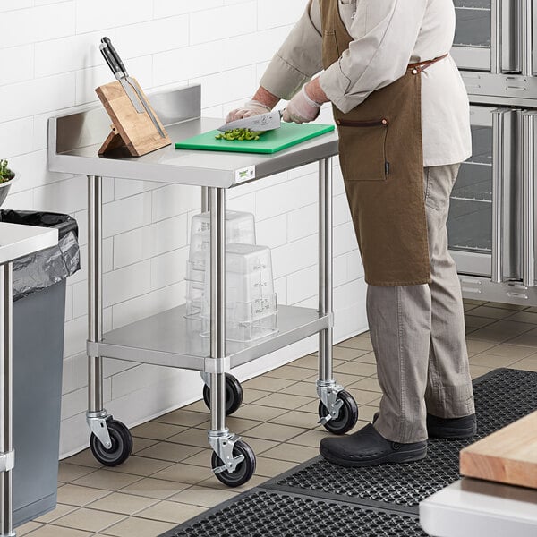 A man cutting vegetables on a Regency stainless steel work table with a backsplash and undershelf.