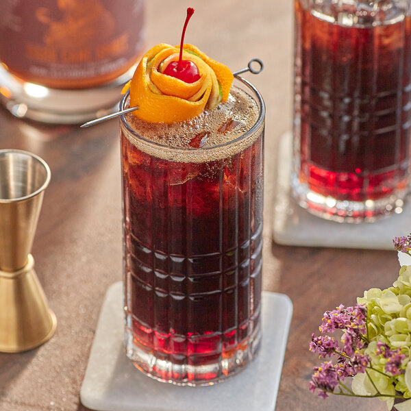 A table set with two glasses of Lyre's Dark Cane Spirit cocktails garnished with fruit.