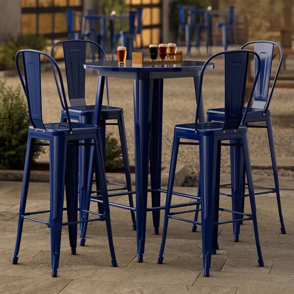 A blue metal bar height table with four blue metal chairs.