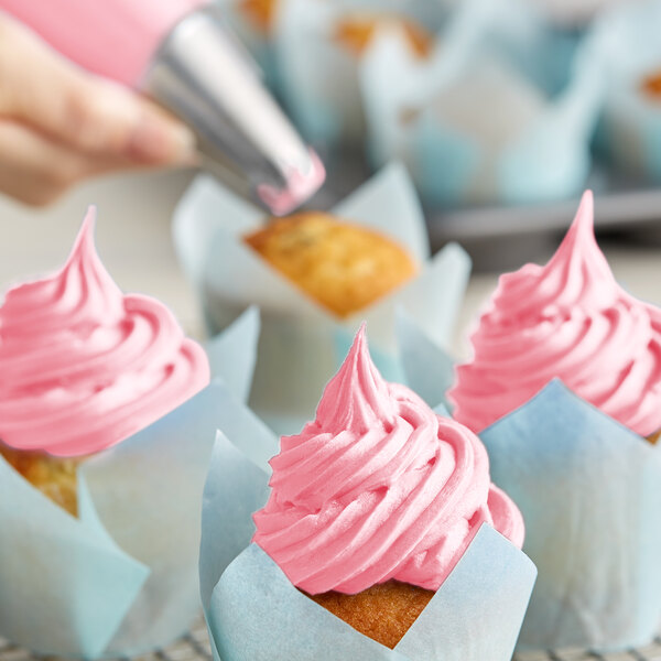 A cupcake with Rich's Allen Pastel Pink Buttrcreme icing and a decorative swirl on top.