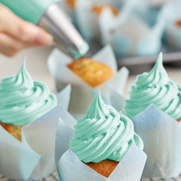 A close-up of a cupcake frosted with mint green Rich's Allen Buttrcreme icing.