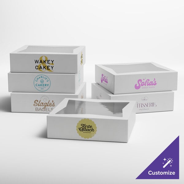 A set of white customizable auto-popup window bakery boxes, each featuring different bakery logos and a clear window on top.