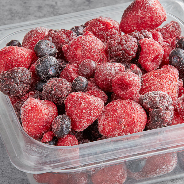 A plastic container of Dole frozen mixed berries.