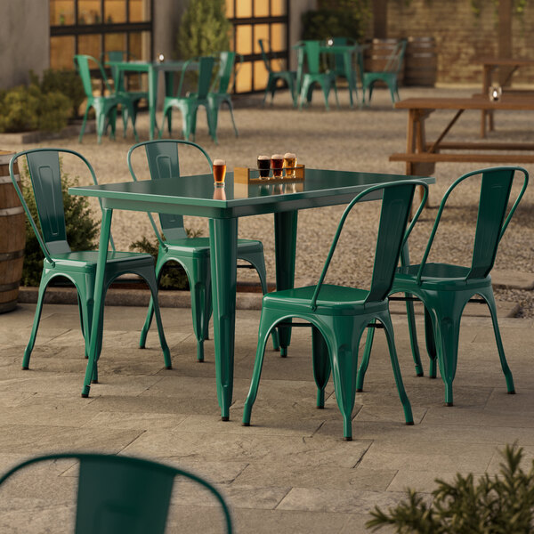 An emerald green Lancaster Table & Seating outdoor table with chairs on a patio.