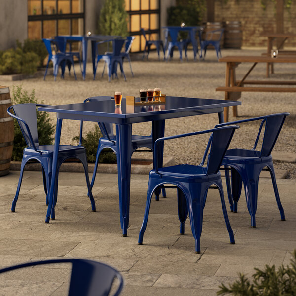 A blue metal Lancaster Table & Seating outdoor table with chairs on a patio.