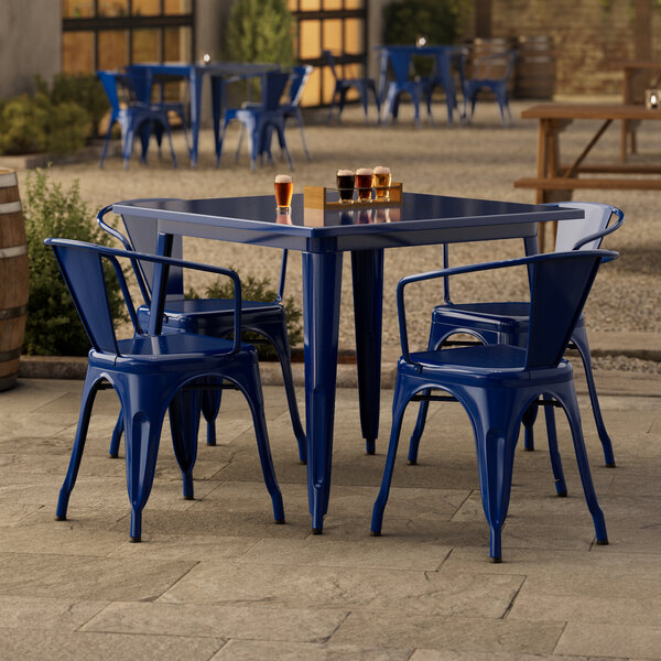 A blue metal table with blue chairs on a stone surface.