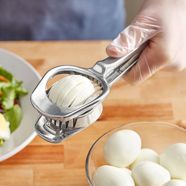 A hand using the Fox Run stainless steel egg slicer to slice a hard boiled egg.