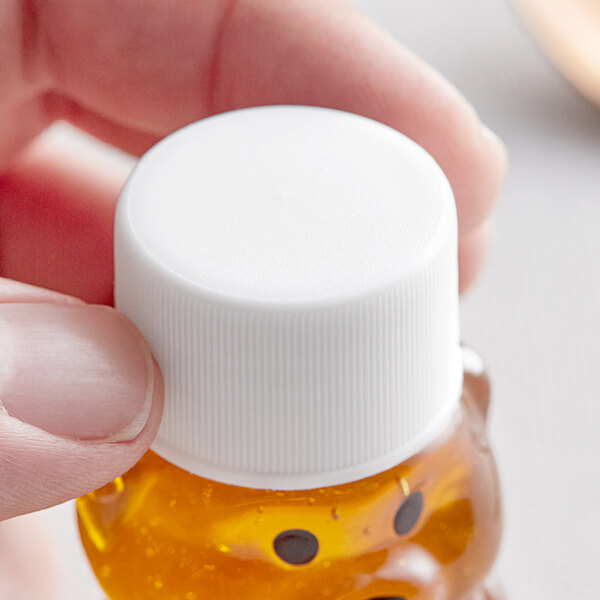 A hand holding a small plastic bottle of liquid with a white lid.