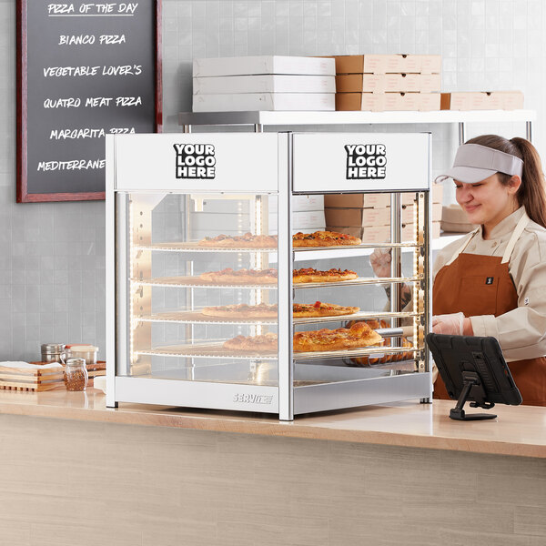 A woman standing behind a counter with food in a ServIt countertop display case.