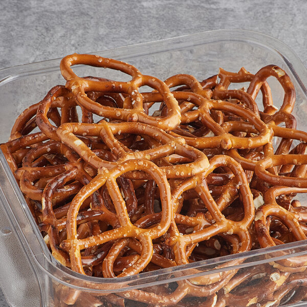 A Tom Sturgis Thin Pretzels container on a table filled with pretzels.