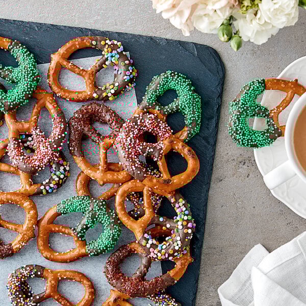 A tray of Tom Sturgis pretzels with green sprinkles on top displayed on a table.