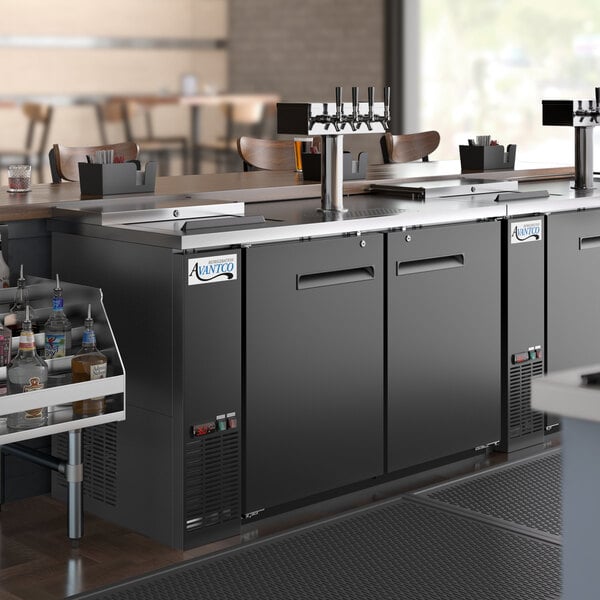An Avantco black kegerator with a quadruple tap tower on a large counter.