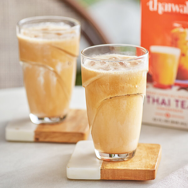 Two glasses of Thaiwala Thai tea on a table.