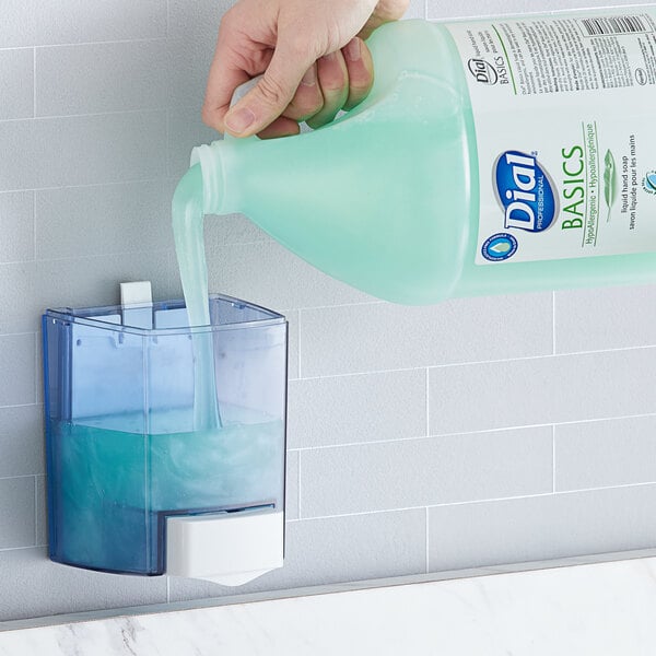 A hand pouring Dial Professional Basics Hypoallergenic Liquid Hand Soap into a soap dispenser.