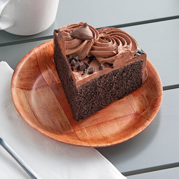 A piece of chocolate cake with frosting on a Choice woven wood plate.