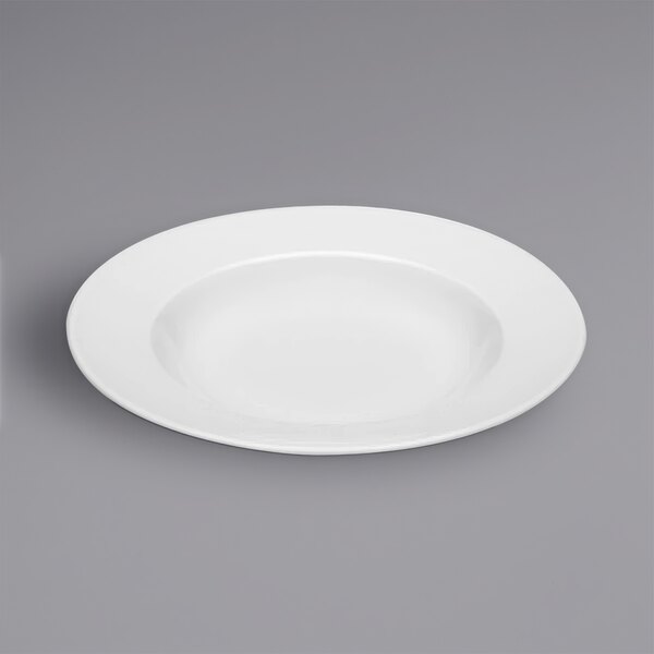 A Bauscher bright white porcelain wide rim deep coupe plate on a gray surface.