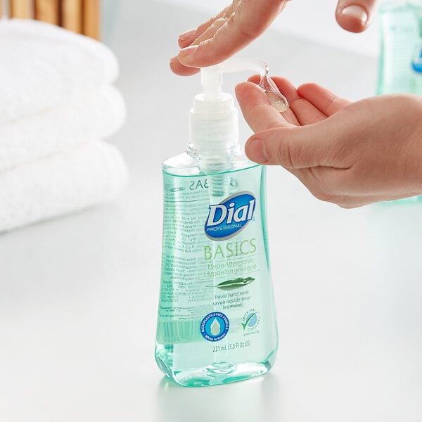 A person using a pump of Dial Hypoallergenic Liquid Hand Soap on a counter.